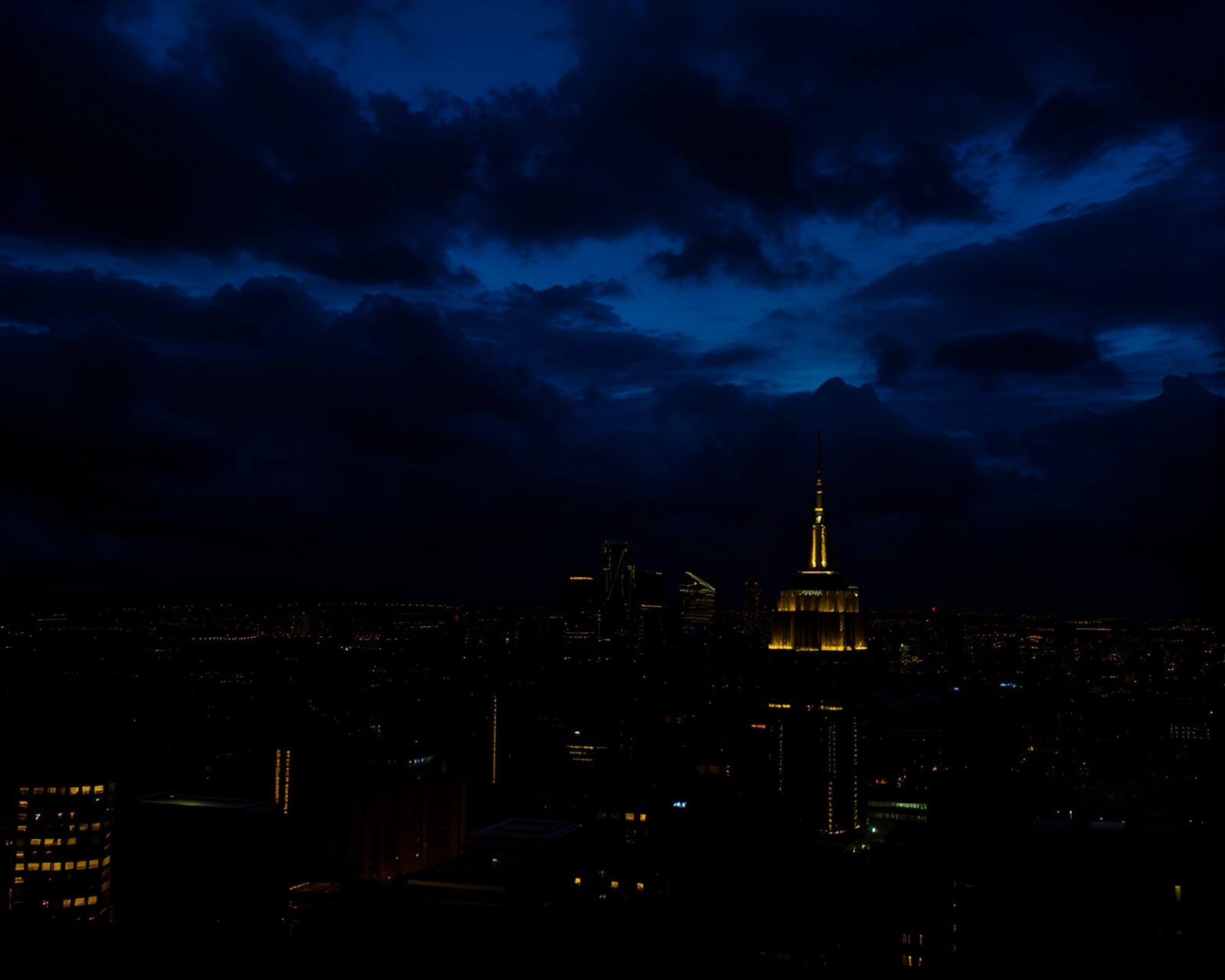 Glowing city lights in dark, ominous urban skyline at dusk