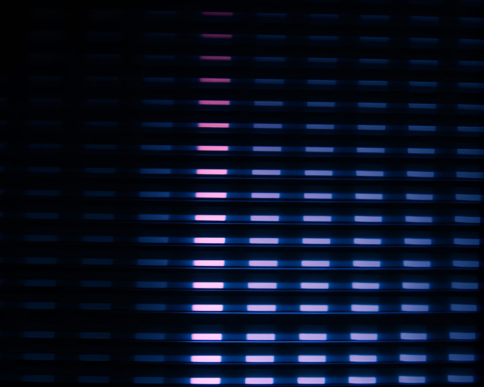 Bold neon sign against striped pattern in dim light