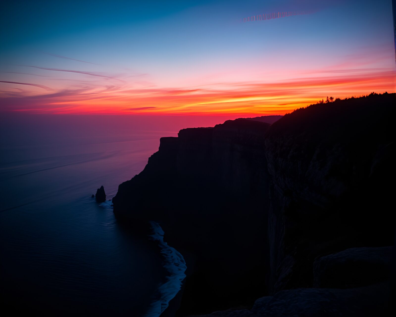 Vibrant neon lights reflect on surreal cliff shadow.