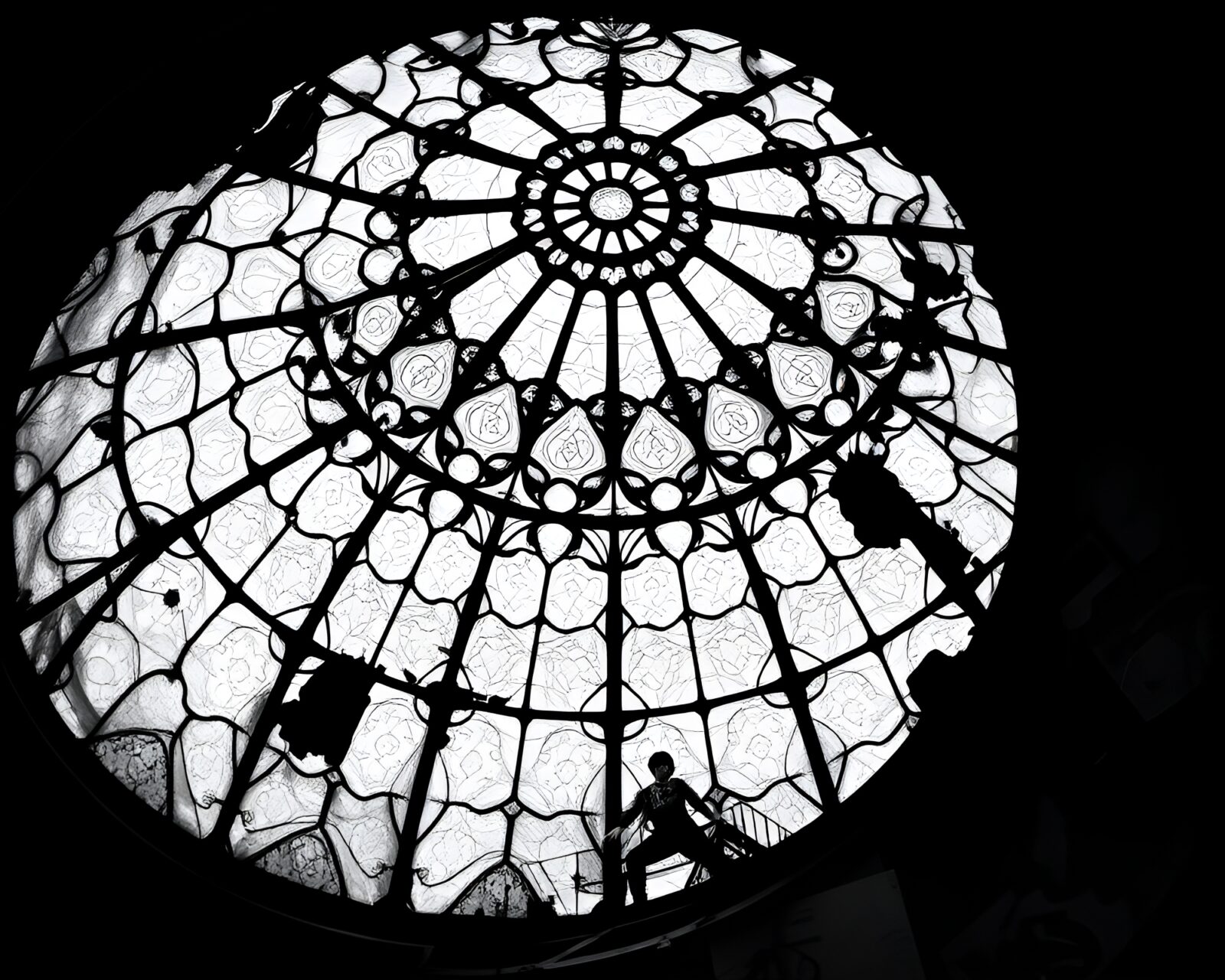 Monochrome image of person under colorful stained glass dome