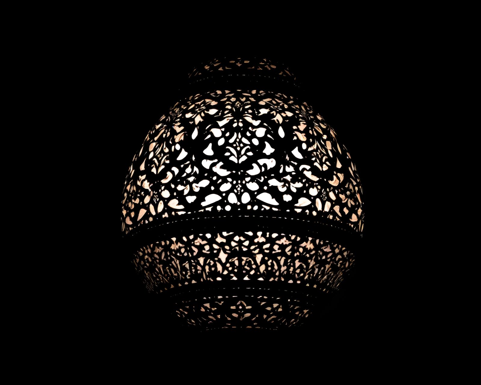 Exquisite beadwork lamp glowing under dramatic engraved lighting