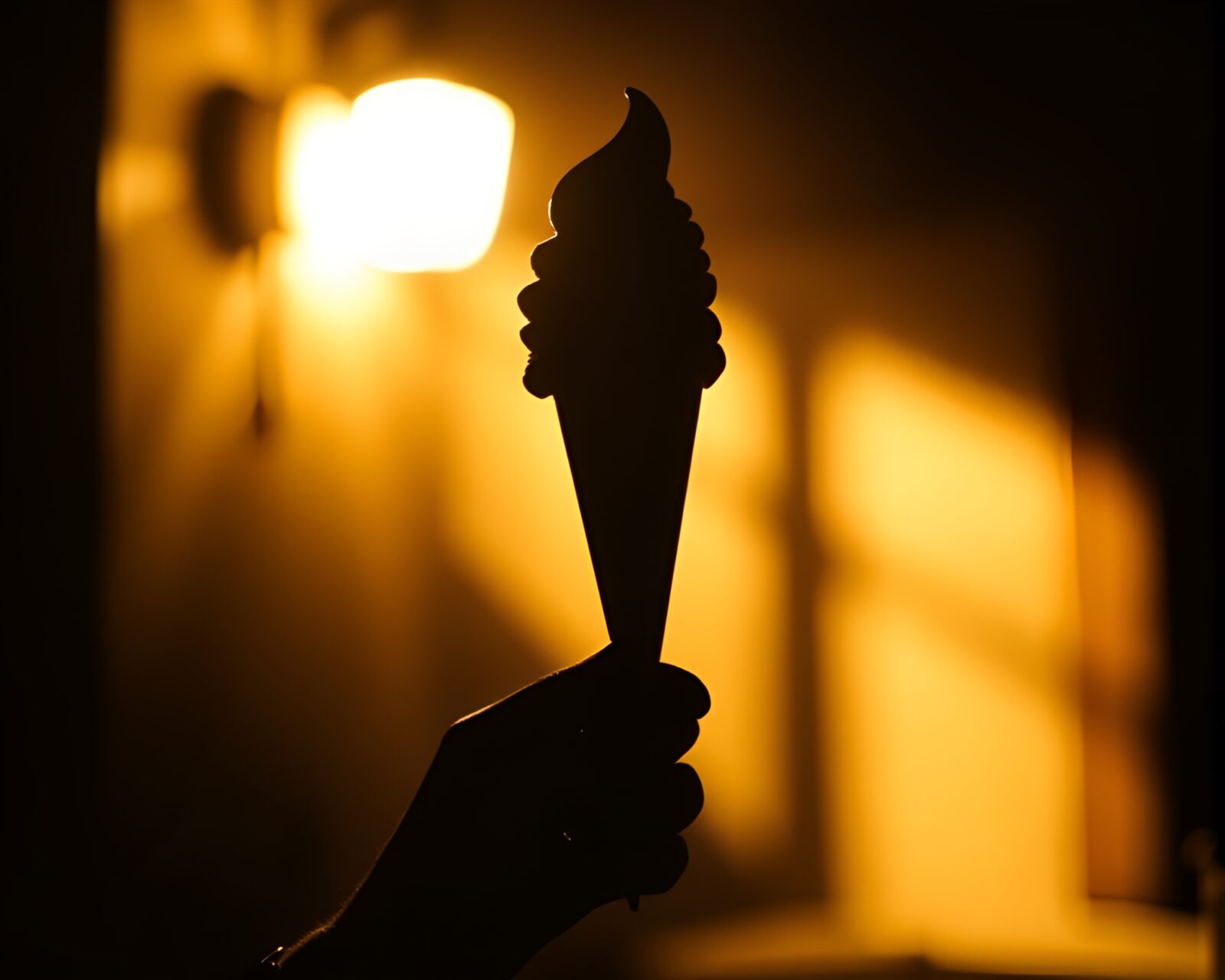 Silhouette of a gelato cone against warm porchlight shadows