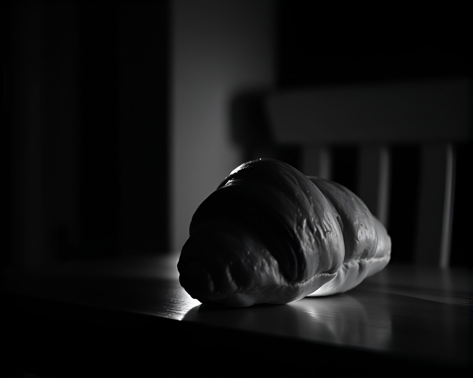 Off-center monochrome croissant lit by warm porchlight glow