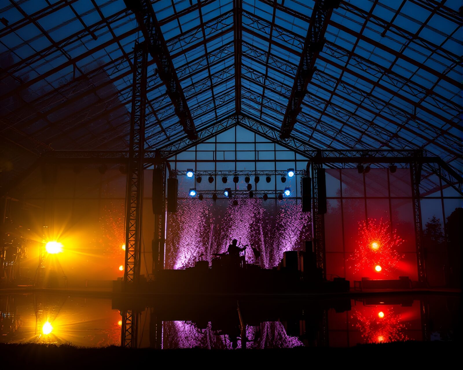 Vividly lit concert stage inside a glass greenhouse with reflections