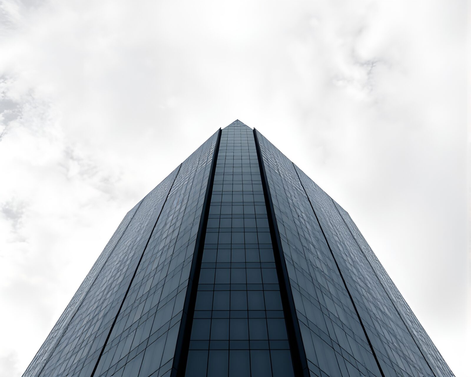 A modern skyscraper reflecting on a calm blue surface
