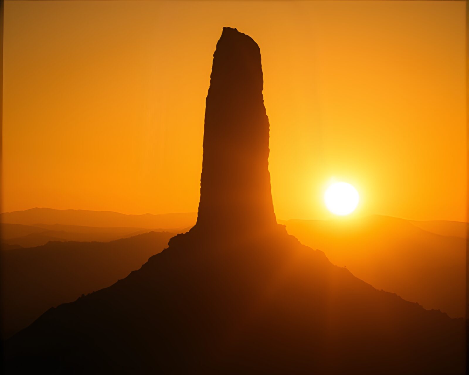 Majestic monolith glowing in golden noir light contrast