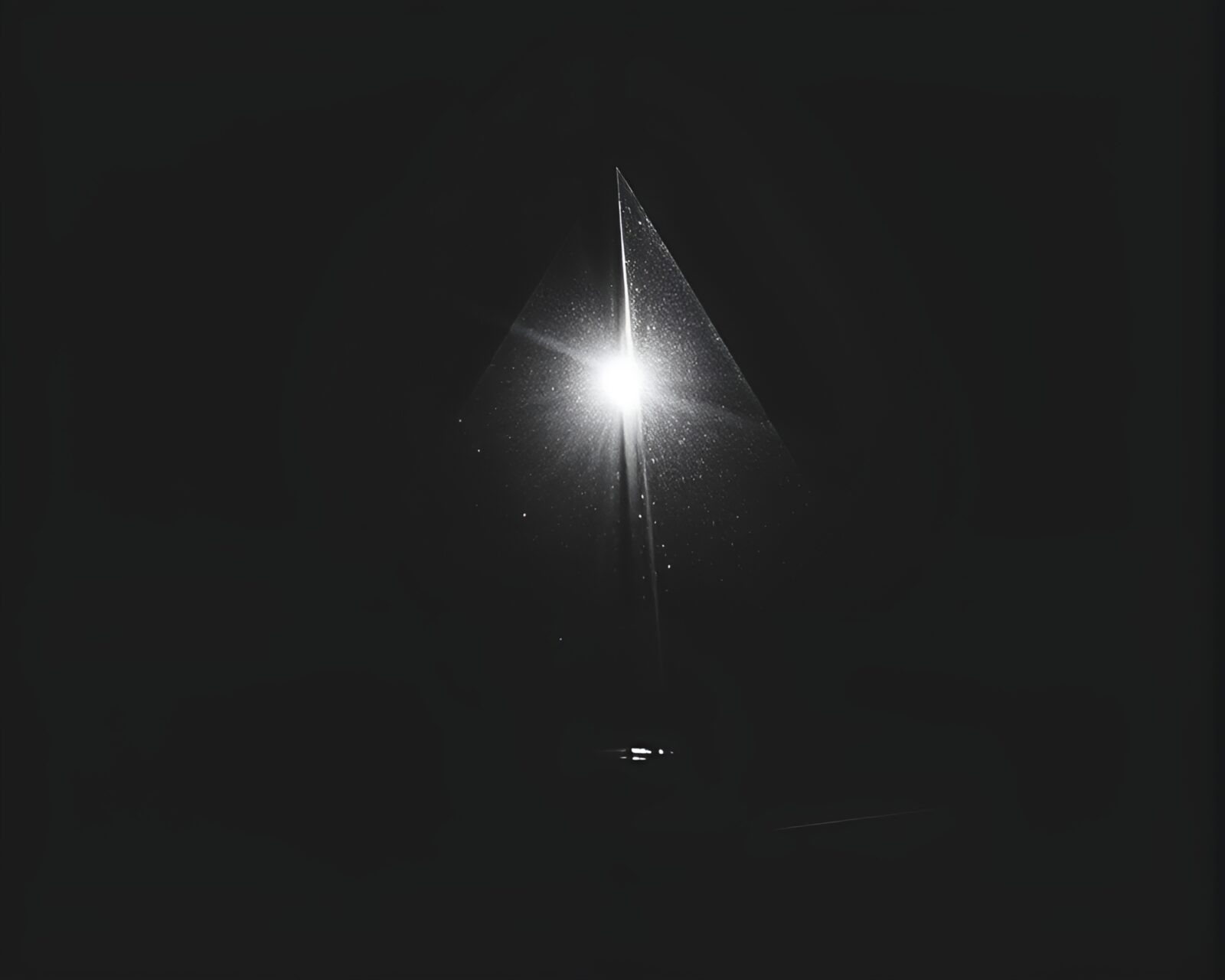 Backlit silhouette of glass pyramid refracting prism light