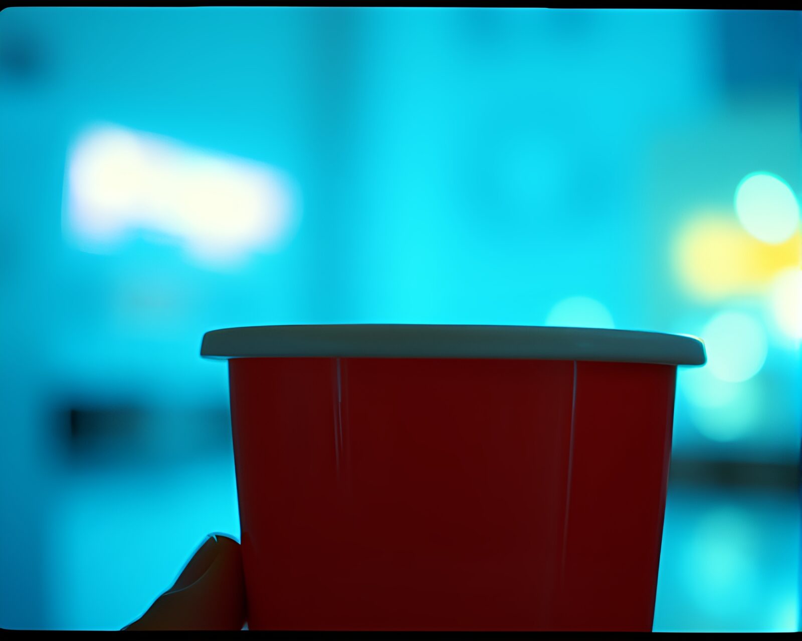 A mesmerizing image of a coffee cup intertwined with film sprocket holes under ice-blue fluorescent lights.