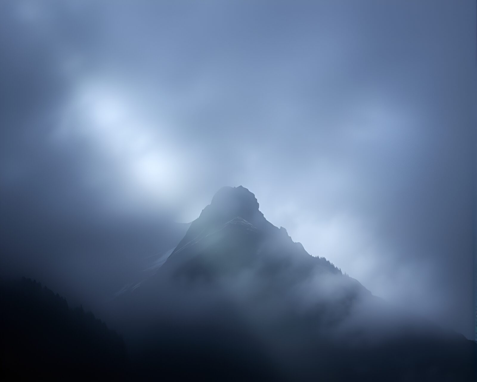 Dramatic mountain peak engulfed in mist under stage illumination