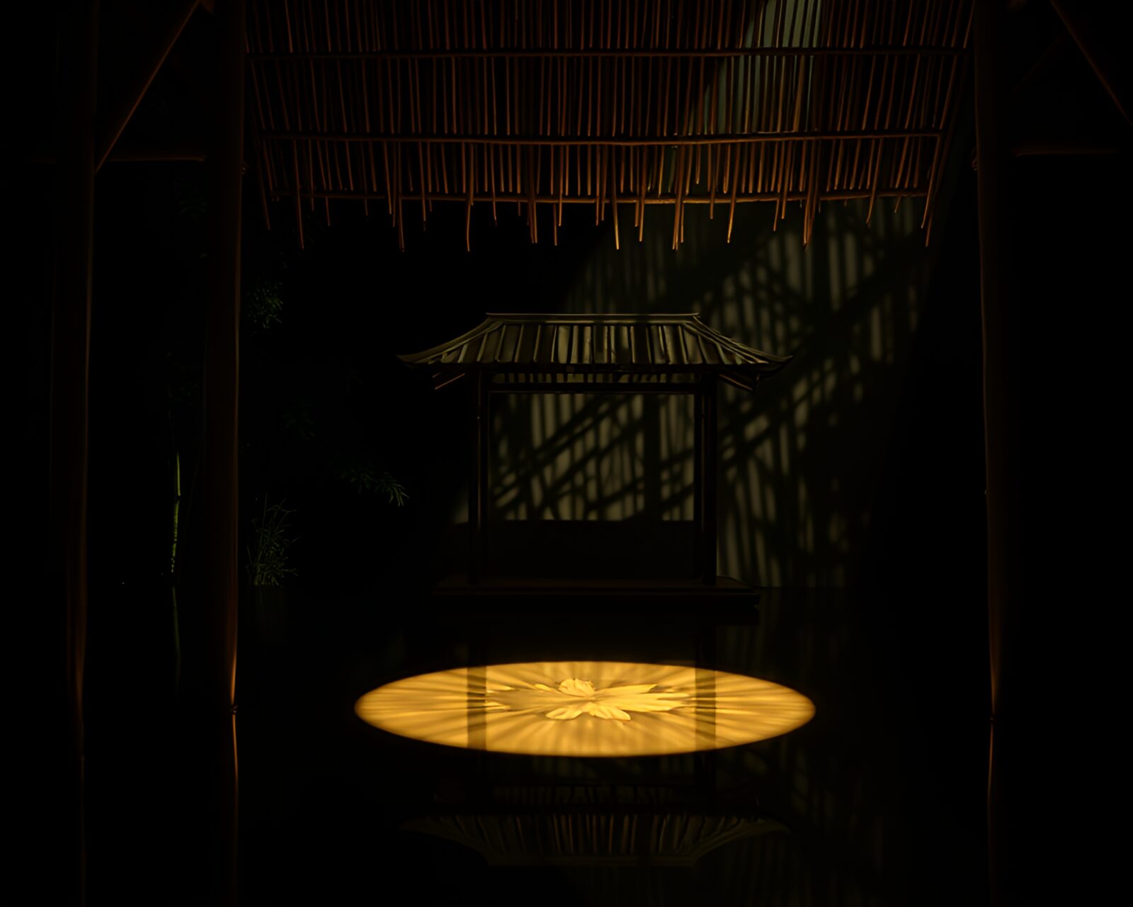 Glowing stage light illuminates intricate bamboo hut etching