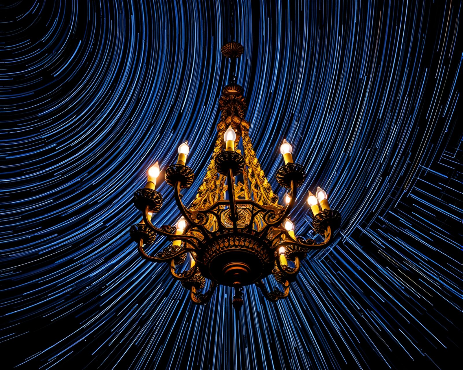 Eerie Gothic chandelier hanging under a night sky filled with star trails