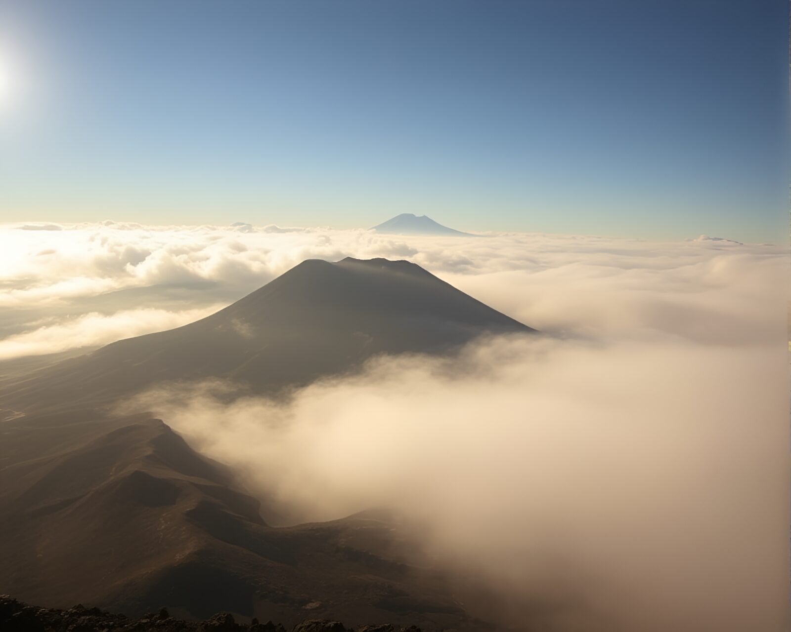Fog drifting over volcano crater in bright midday light