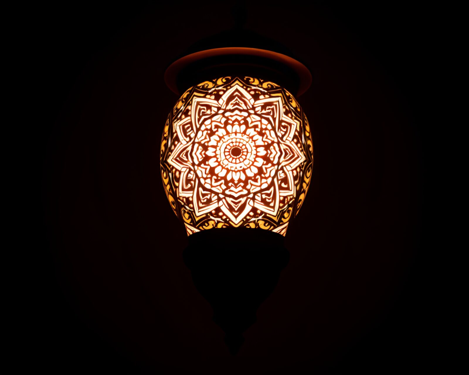 Intricate mandala design illuminated by lantern light in telephoto shot