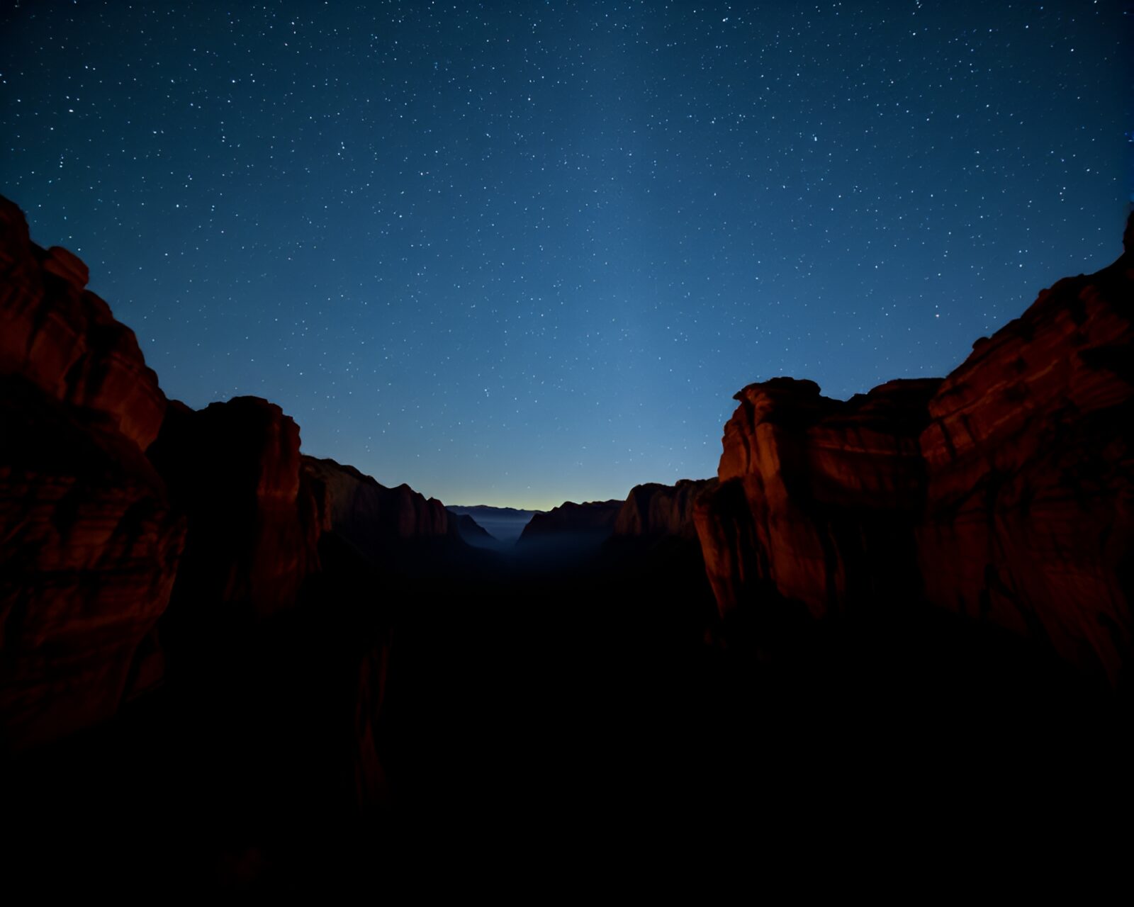 Silhouettes against a star-filled canyon vista at night