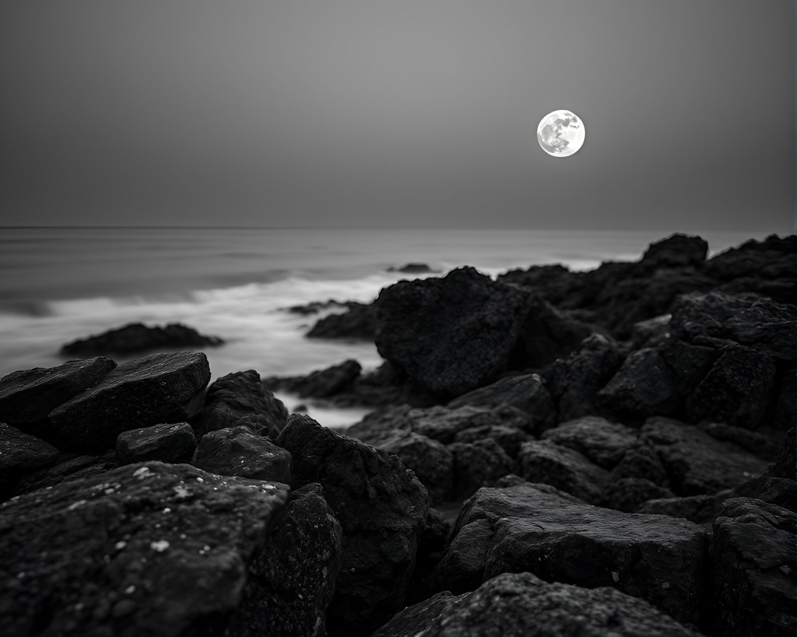 Dreamy grayscale image of a rocky coast in the moonlight